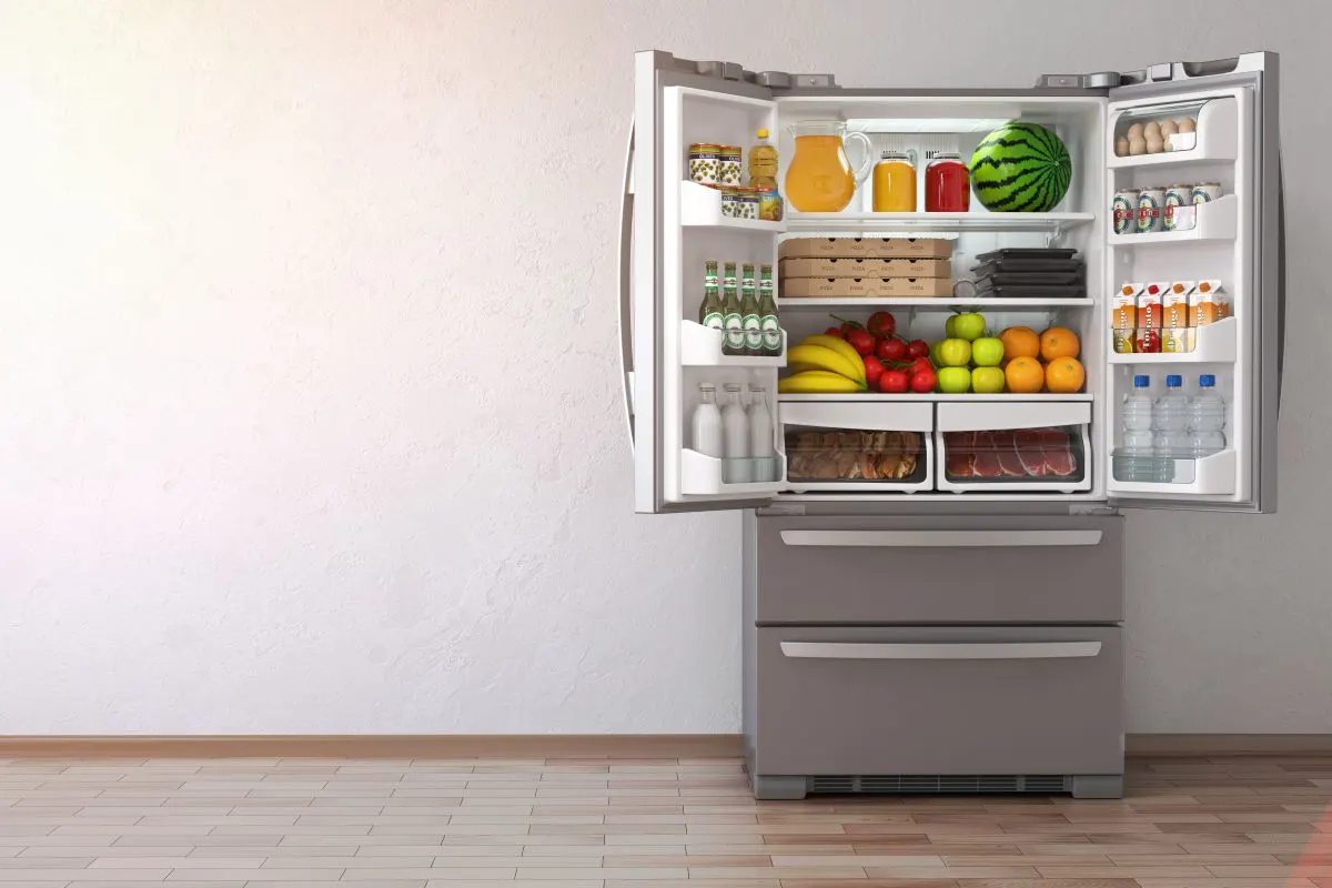 Frigorifero side‑by‑side con porte aperte, pieno di frutta, verdura e carne.