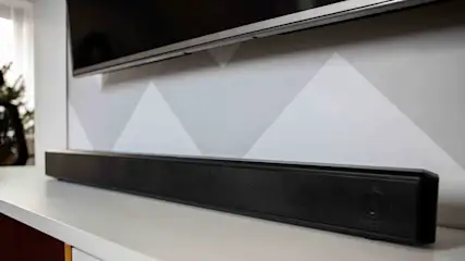 Soundbar su un mobile TV sotto un televisore a parete.