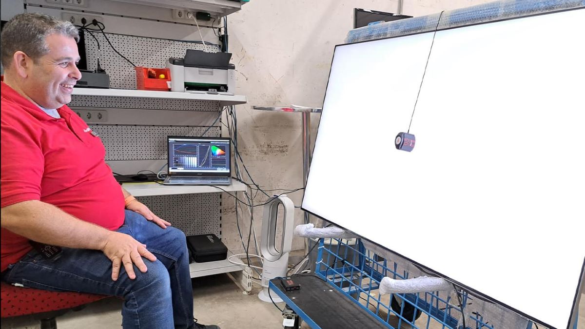 Un tecnico di MediaMarkt calibra un grande televisore a schermo piatto.