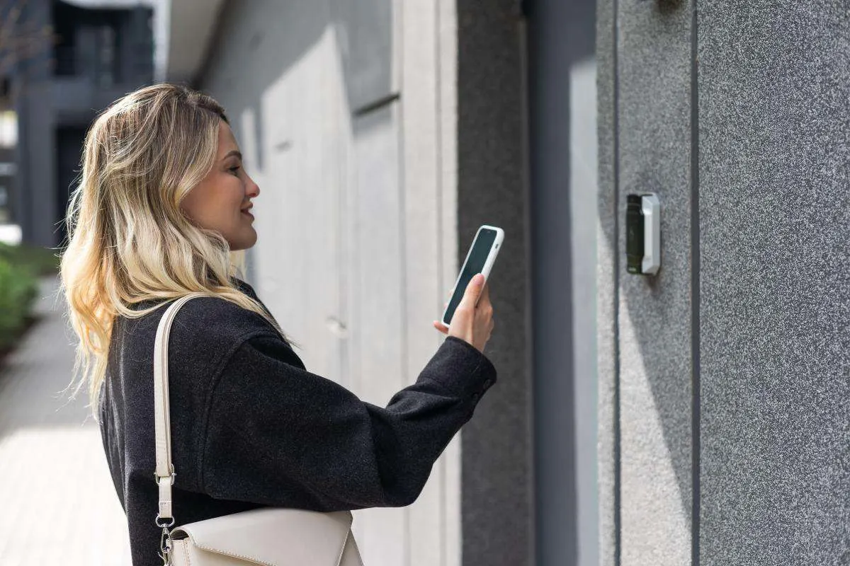 Una donna sblocca una serratura smart con lo smartphone. 