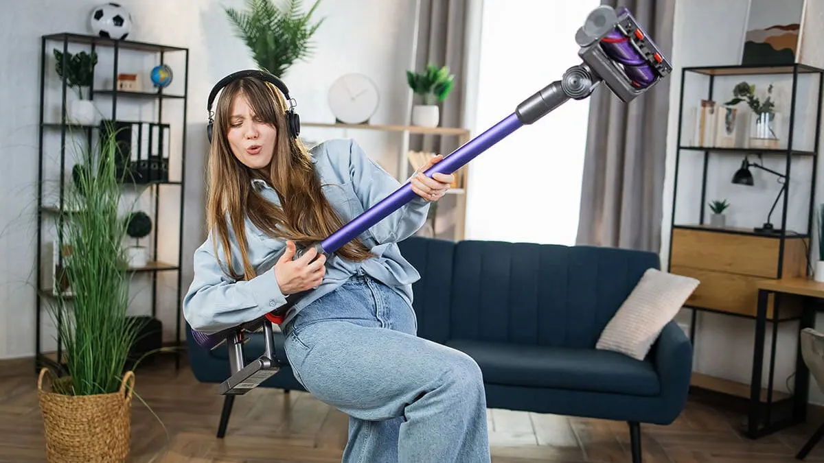 Une femme danse avec un aspirateur sans fil