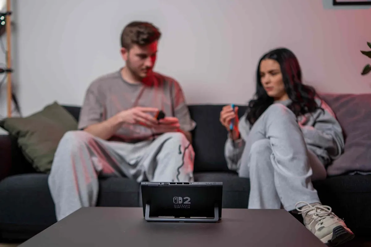 Zwei Spieler sitzen auf dem Sofa und spielen gemeinsam ein Multiplayer-Spiel auf der Nintendo Switch 2, die auf dem Tisch steht.