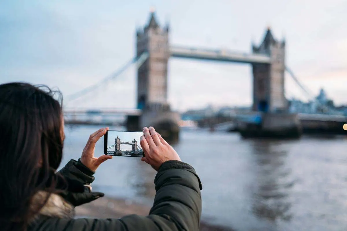 Frau fotografiert die Tower Bridge in London mit ihrem Smartphone.