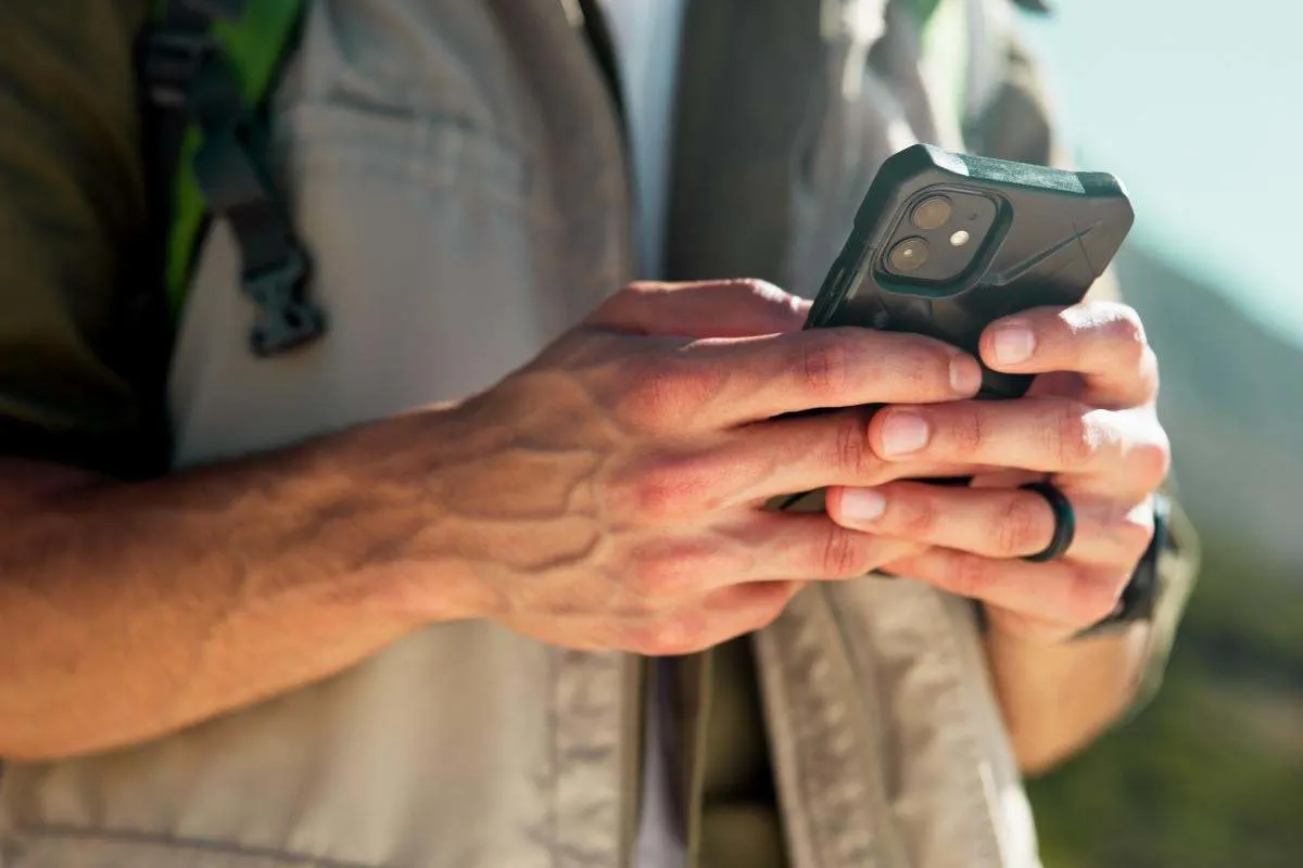Un escursionista tiene in mano uno smartphone outdoor.