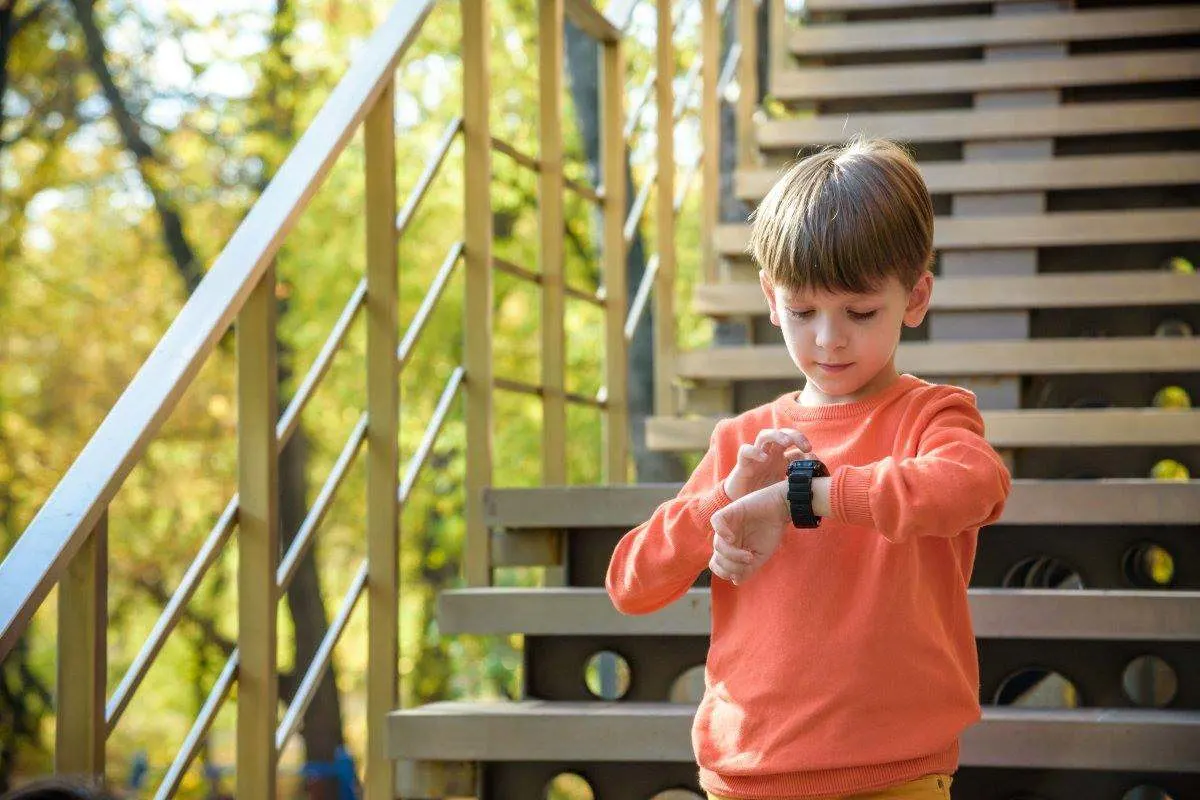 Un bambino guarda il suo smartwatch per bambini al polso mentre è in giro.