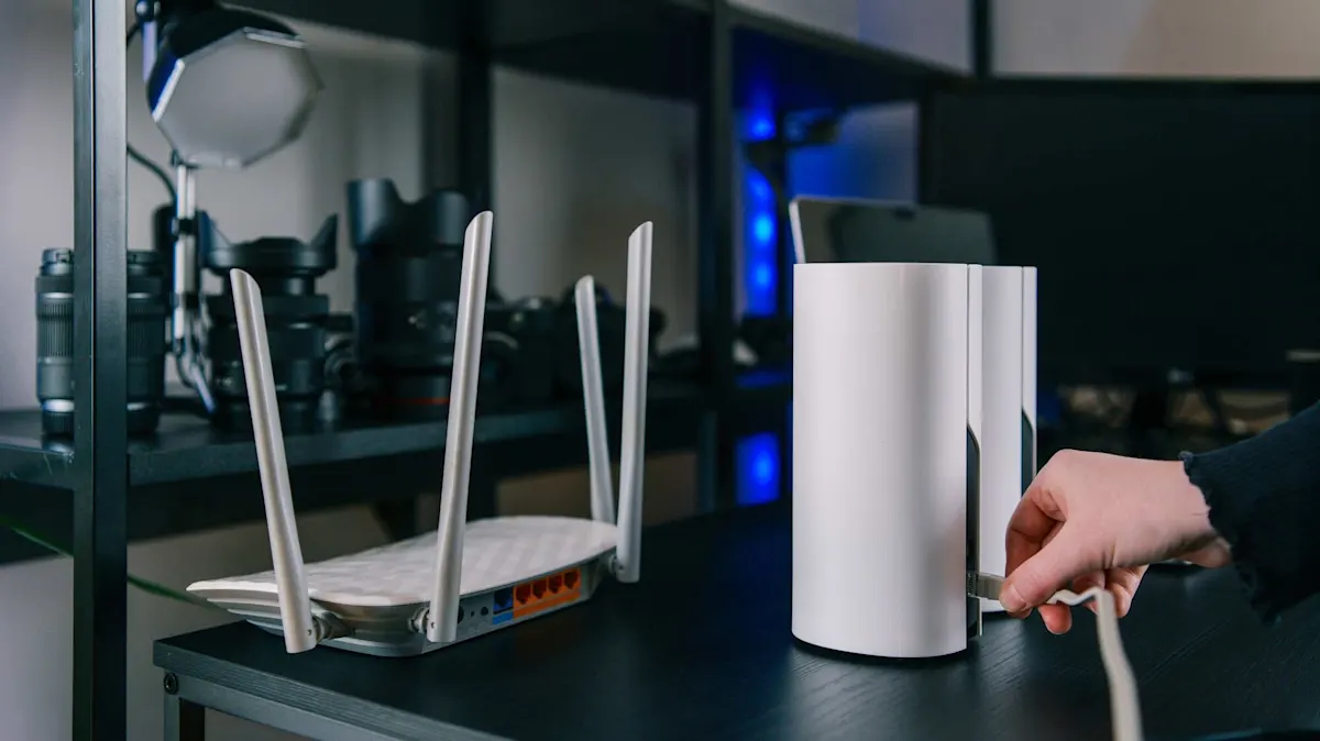 WLAN-Router und Mesh-System auf einem Tisch, während eine Person ein Netzwerkkabel in das Mesh-Gerät einsteckt. 