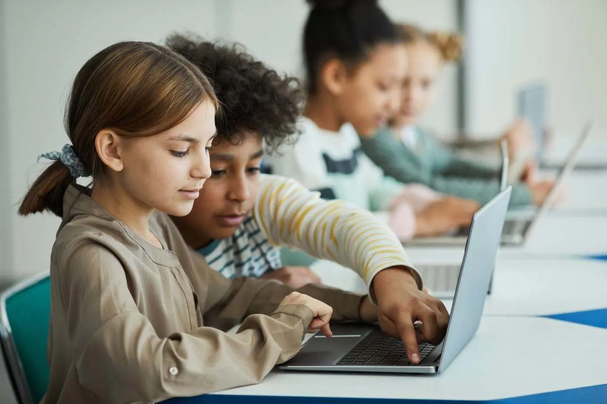 Zwei Schüler arbeiten gemeinsam an einem Laptop und nutzen das Gerät für den digitalen Schulalltag. 