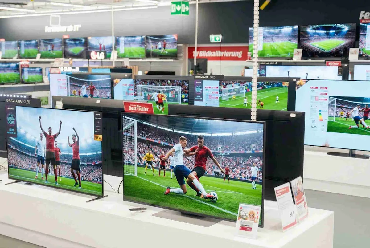 De nombreux téléviseurs dans un magasin d’électronique, affichant un match de football. 