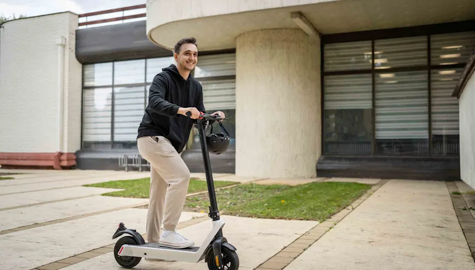 Uomo sorridente mentre sale su un e-scooter.