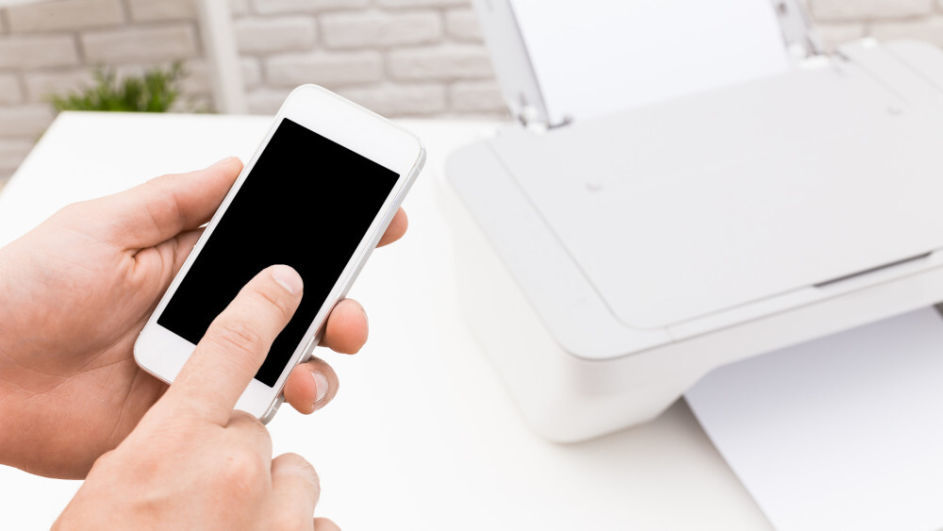 Eine Person verbindet sein Smartphone mit seinem weißen Drucker.