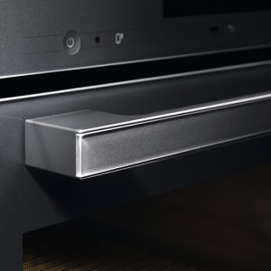 Nahaufnahme eines Ofens mit einem rechteckigen, silberfarbenen Griff an einer schwarzen Ofentür.