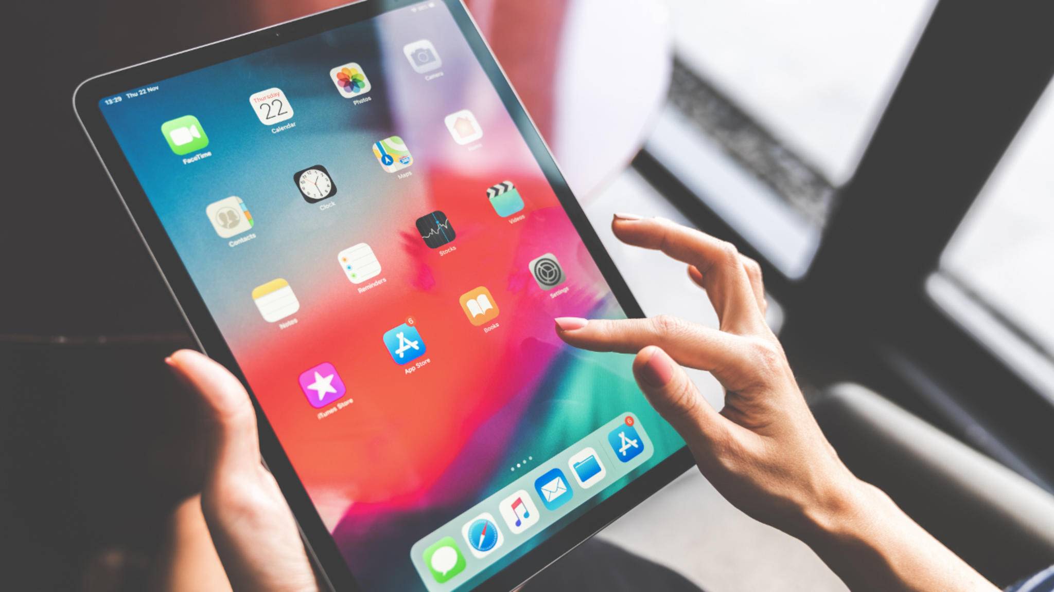Eine Person bedient ein iPad, auf welchem der Startbildschirm zu sehen ist.