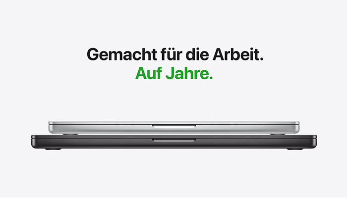 Zwei übereinander liegende MacBooks in Silber und Dunkelgrau in Seitenansicht. Text: „Gemacht für die Arbeit. Auf Jahre.“