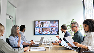 Mitarbeiter bei einem Live-Videomeeting im Konferenzraum.