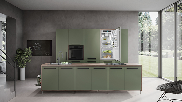 Eine grüne Küche mit Spüle, Herd und offenem Kühlschrank steht vor einem großen Fenster mit Blick auf einen Garten.