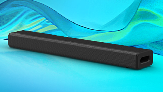 Ein schwarzer, quaderförmiger Lautsprecher liegt auf einer blaugrünen Oberfläche mit abstraktem, blauem Hintergrund.