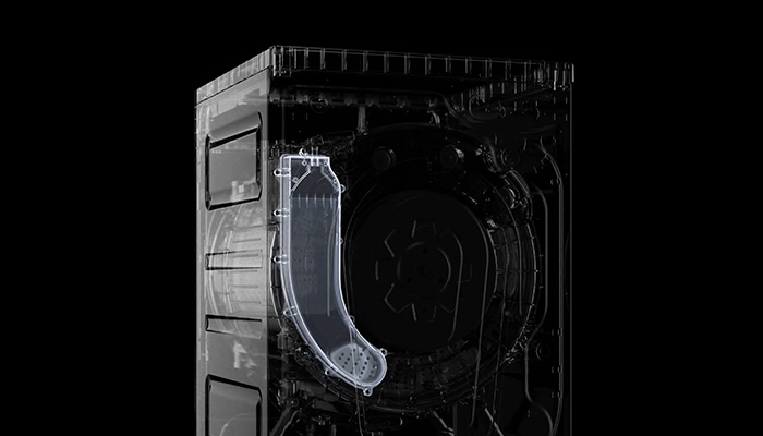 Eine durchsichtige Waschmaschine mit einem Wasserbehälter an der Seite vor einem dunklen Hintergrund.