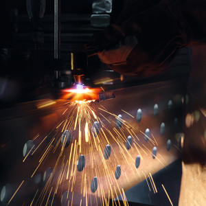 Metallschneidemaschine in Betrieb, Funken fliegen von orangefarbenem Licht auf dunklem Hintergrund.