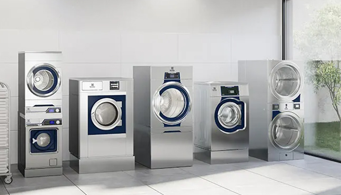 Mehrere Waschmaschinen und Trockner von Electrolux Professional stehen nebeneinander in einem weiß gekachelten, hellen Raum.