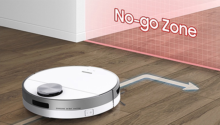 Auf einem Holzboden steht ein runder, weißer Staubsaugerroboter mit silbernen Akzenten, der eine Richtung andeutet.