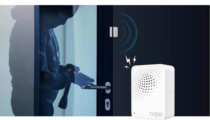 Einbrecher an Tür mit Sensor und weißem Gerät. Türsensor sendet Signal an Gerät. Das Gerät ist mit "tapo" gekennzeichnet.