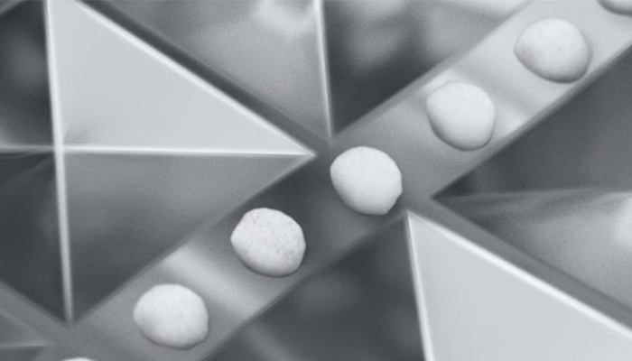 Eine Nahaufnahme in Graustufen zeigt eine Reihe runder, weißer Objekte, die sich auf einem schmalen, diagonalen Pfad bewegen, der von dreieckigen, metallischen Formen umgeben ist.