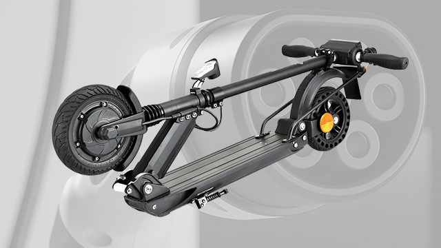 Ein zusammengeklappter, grauer Elektroroller mit schwarzem Reifen und Trittbrett vor einem verschwommenen, grauen Hintergrund.