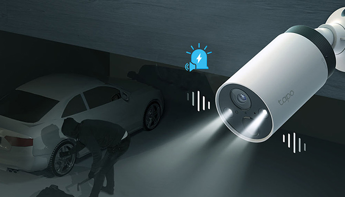 Eine Überwachungskamera leuchtet eine Person neben einem Auto an, während ein blaues Alarmsymbol angezeigt wird.