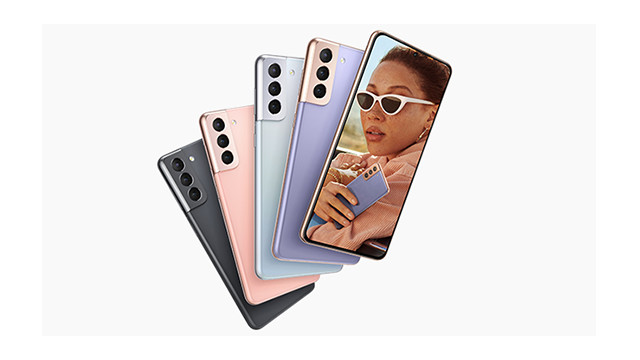 Fünf Smartphones in Schwarz, Rosa, Silber und Lila liegen übereinander. Das Display zeigt eine Frau mit Sonnenbrille, die ein Handy hält.
