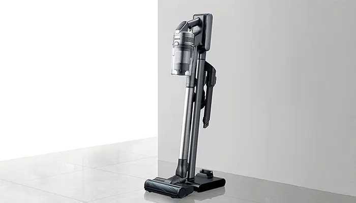 Ein grauer Staubsauger steht auf einer grauen Oberfläche vor einem hellen Hintergrund.