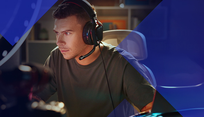 Ein Mann sitzt vor seinem PC, trägt ein Headset und spielt.