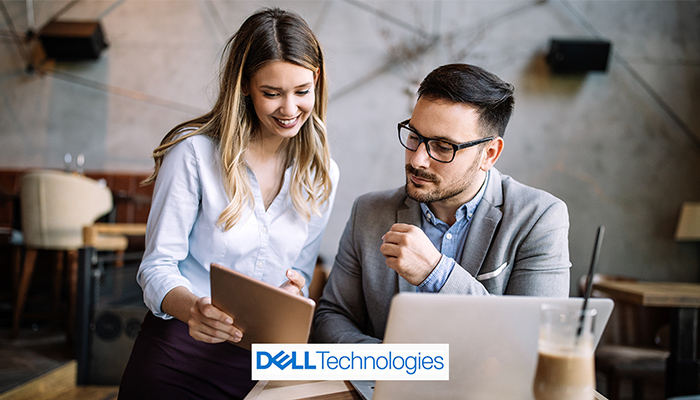 Eine Frau zeigt einem Mann mit Brille etwas auf einem Tablet. Ein Laptop und ein Getränk stehen auf dem Tisch. Logo in Mitte: Dell Technologies.