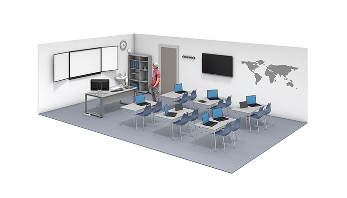 Blick in ein modernes Klassenzimmer mit Laptops auf den Tischen. Ein Schüler steht in der Mitte des Raumes und schaut auf die digitale Tafel. 