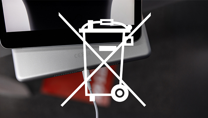 Ein Tablet mit schwarzem Bildschirm und silbernem Gehäuse wird mit einem weißen Kabel geladen. Ein durchgestrichenes Mülltonnen-Symbol ist abgebildet.