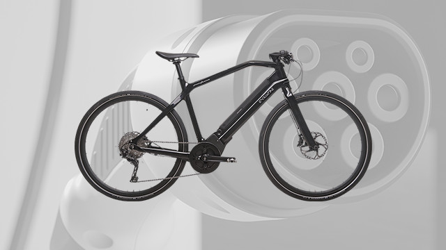 Ein schwarzes Fahrrad steht vor einem runden, unscharfen Hintergrund mit mehreren Löchern darin.