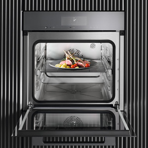 Ein offener, silberfarbener Ofen mit einem Gericht auf einem Rost. Der Hintergrund zeigt eine Wand mit schwarzen Streifen.