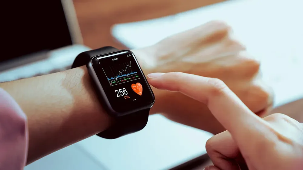 Eine Person tippt auf eine Smartwatch, welche sie am Arm trägt.