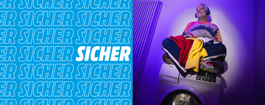 Ein Mann mit Kopfhörern sitzt auf einer Waschmaschine mit Wäsche, vor einem Hintergrund mit dem Wort "SICHER".