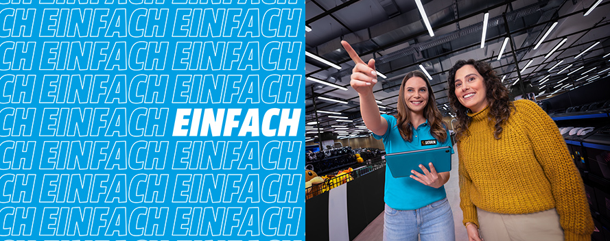 Zwei Frauen in einem Lagerhaus; eine zeigt mit dem Finger nach oben, die andere lächelt. Logo-Muster auf der linken Seite.