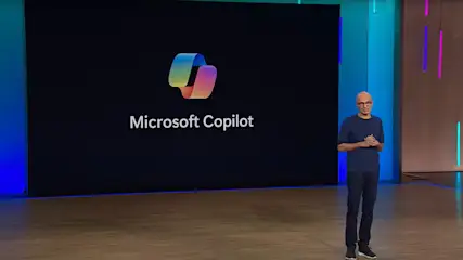 Ein Mann steht vor einem Bildschirm mit dem Microsoft Copilot Logo und dem Text "Microsoft Copilot".