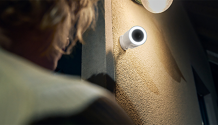 Eine Hama-Außenkamera, die an einer Hausfassade angebracht ist und die einen Menschen im Blick hat.