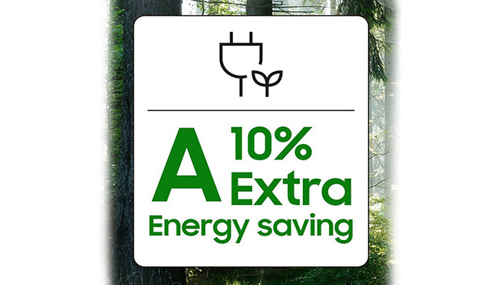 Ein weißes Schild zeigt ein Stecker-Symbol, "10% Extra" und "Energy saving" in grüner Schrift, vor einem verschwommenen Hintergrund mit Bäumen.