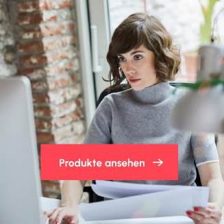 Mitarbeiterin arbeitet konzentriert am Schreibtisch am Computer und hält Unterlagen in der Hand; im Vordergrund ein Button mit der Aufschrift „Produkte ansehen“.