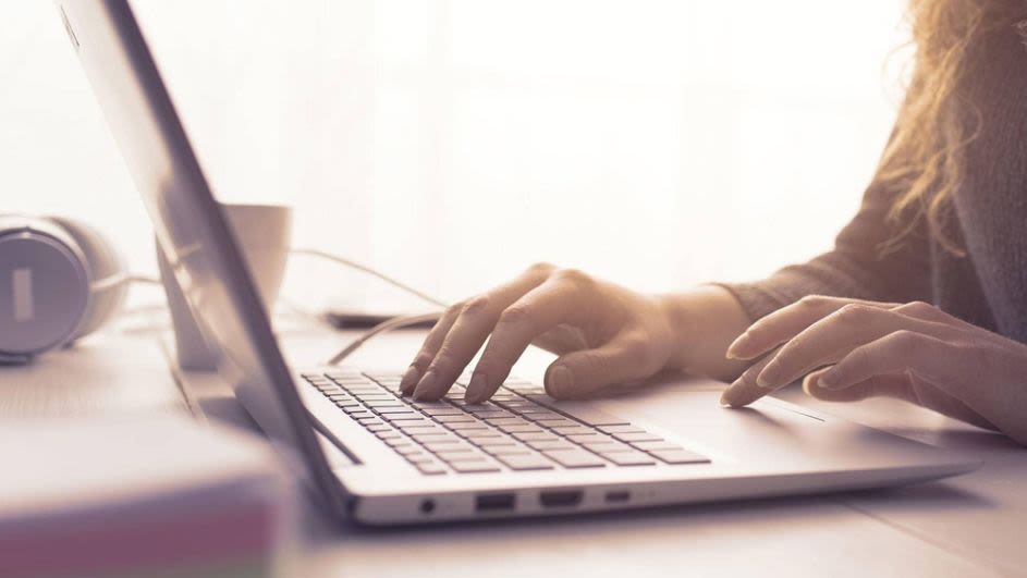 Eine Frau tippt auf einem Laptop und bedient das Touchpad.