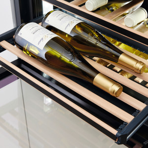 Weinregal mit grünen Flaschen und weißen Etiketten auf Holzregalen, goldene Kapseln, diagonale Anordnung.