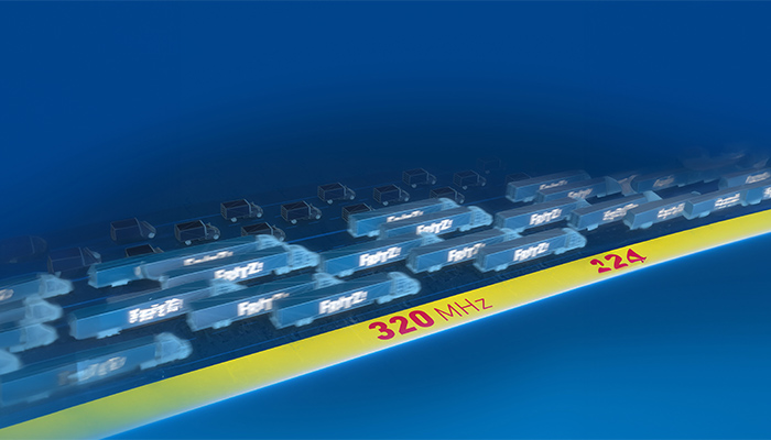 Auf blauem Grund, gelber Streifen mit "320 MHz" und "224", darüber FRITZ!-Logos auf fahrenden LKWs als Symbol der Datenübertragung.