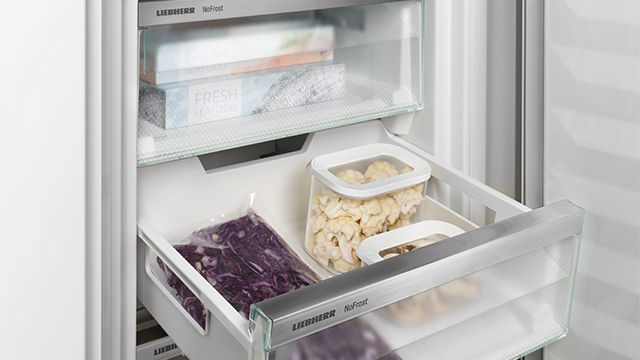 Gefrierschrank mit Schubladen, gefüllt mit verpackten Lebensmitteln, darunter Rotkohl und Blumenkohl.