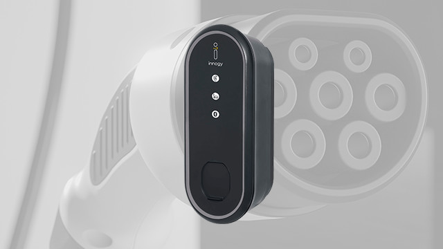 Nahaufnahme eines grauen Ladesteckers mit ovalem, schwarzem Bedienfeld mit drei runden Lichtern und einem Knopf.