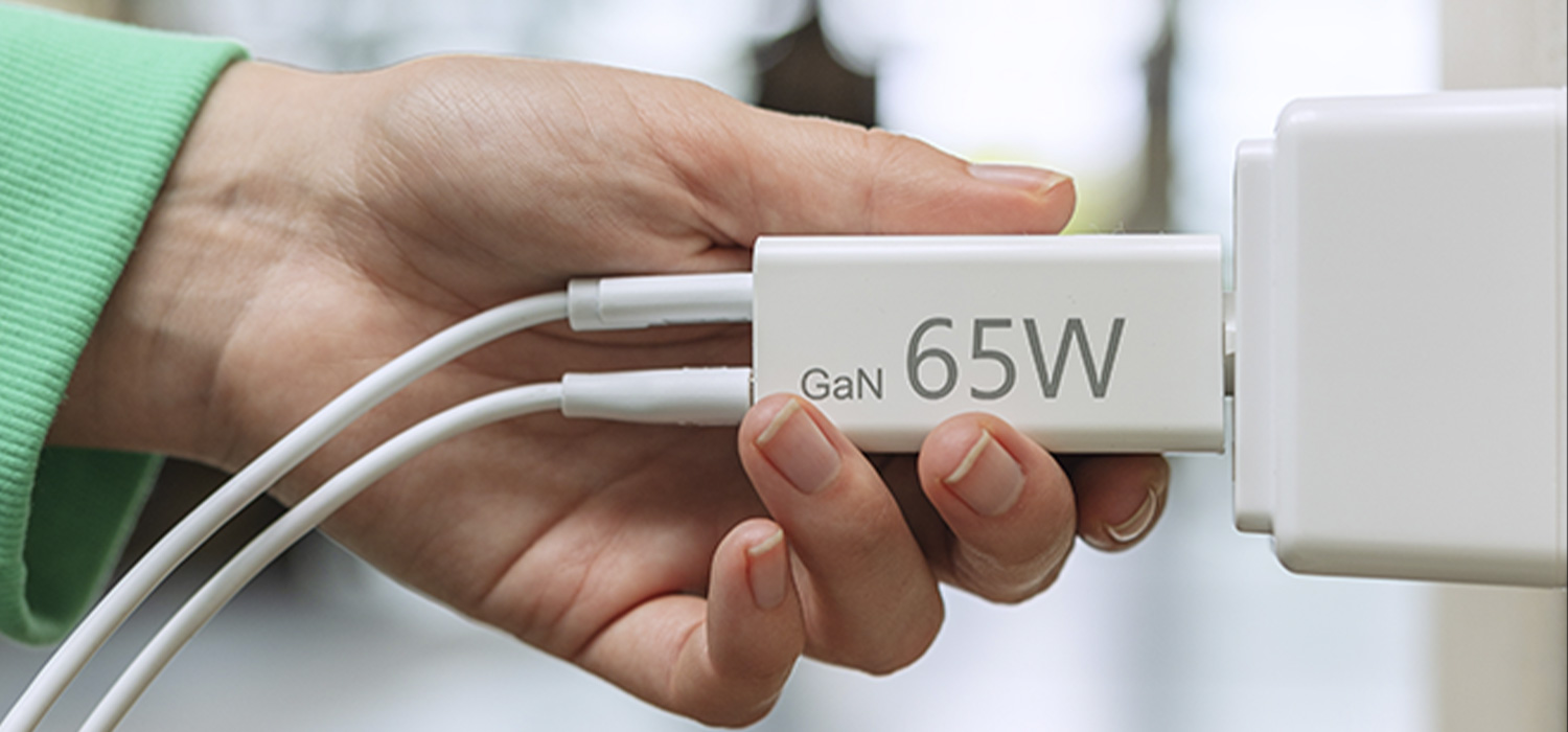 Eine Hand führt den Stecker eines Schnellladegeräts in die Steckdose.