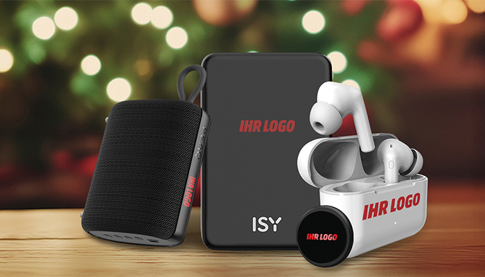 Bluetooth-Lautsprecher und kabellose Kopfhörer mit Platzhalter für Firmenlogo-Aufdruck auf Holztisch vor unscharfem Weihnachtslichtern im Hintergrund. 